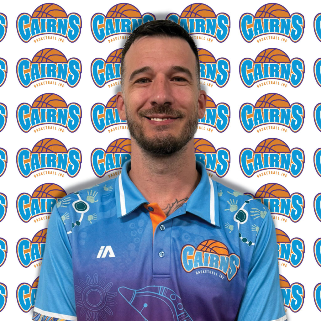 Close-up of a smiling man wearing a blue shirt, with Cairns Basketball logos repeating in the background.
