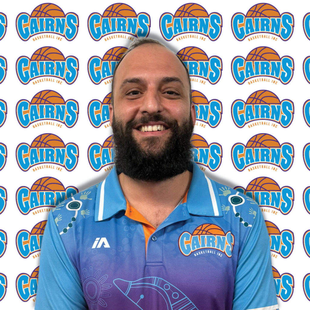 Close-up portrait of a smiling man with a beard in front of a Cairns Basketball backdrop wallpaper