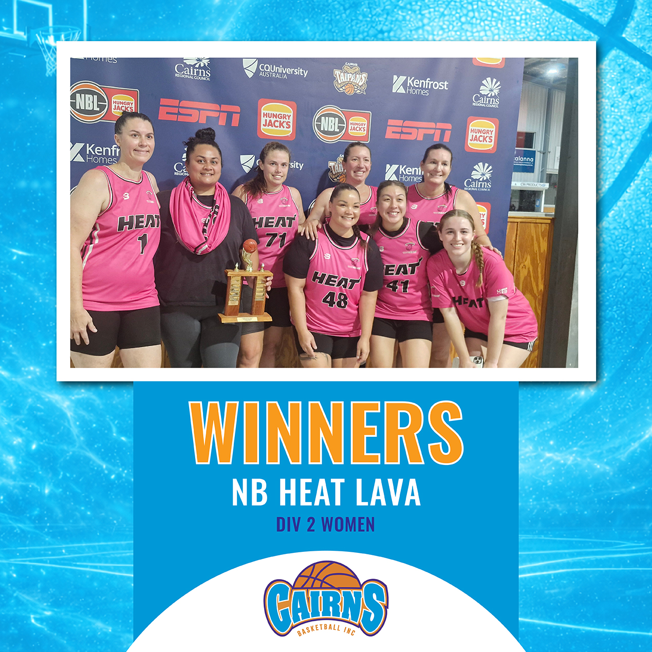 Basketball team in pink jerseys posing with trophy after winning a division, smiling at the camera.