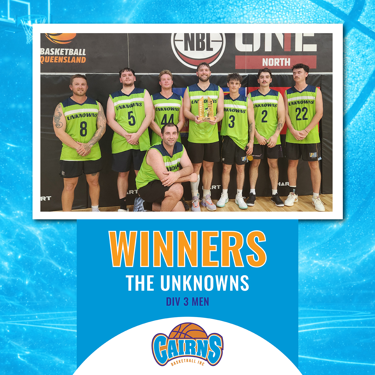 A group of seven male basketball players in neon green jerseys posing on a court, one kneeling front, holding a trophy; winners photo for Division 3 men.